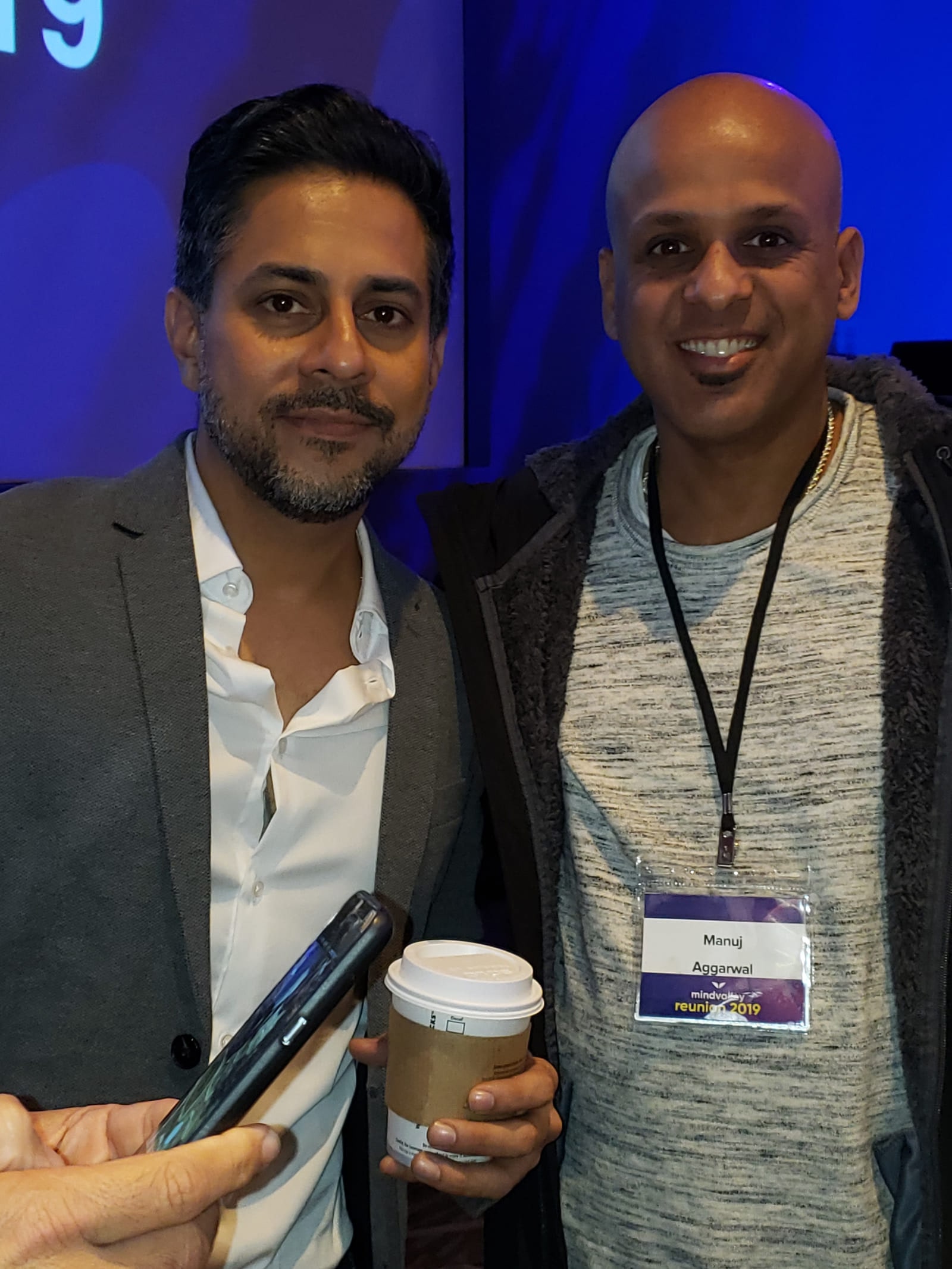 Manuj Aggarwal wearing a conference name badge reading Manuj Aggarwal, standing beside another attendee at the Mindvalley reunion.
